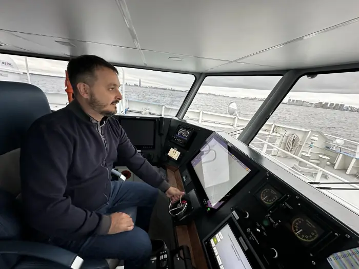 One of Roadstead's founders on a ship bridge in 2026, at the helm with the port skyline ahead