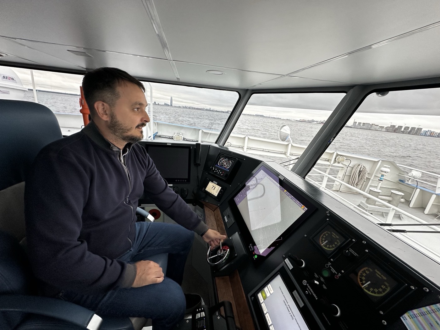 One of Roadstead's founders on a ship bridge years later, at the helm with the port skyline ahead